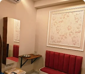 Red upholstered seating and a small table in the GUDVELA guest room